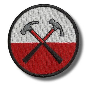 Op de afbeelding: Geborduurde patch met een cirkelvormig ontwerp met een witte bovenste helft en een rode onderste helft. Twee grijze hamers met rode handvatten zijn in het midden gekruist, omlijnd in zwart. De patch heeft een zwarte rand.