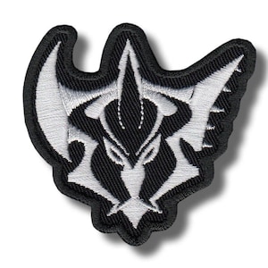Pode incluir: Patch bordado com um design estilizado em preto e branco. O patch tem uma borda preta e um design complexo e simétrico em fio branco. O elemento central do design assemelha-se a uma cabeça de animal ou emblema estilizado.