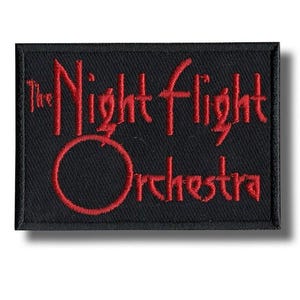 Könnte beinhalten: Ein rechteckiger, schwarzer Aufnäher mit dem in Rot gestickten Schriftzug "The Night Flight Orchestra". Der Text ist in einer stilisierten Schriftart gehalten, mit dem Wort "Orchestra" unter einem großen roten Kreis.