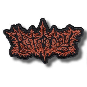 Peut inclure: Écusson brodé avec une bordure noire et un motif de texte stylisé de couleur rouille. Le patch a un bord dentelé et un effet d'ombre, lui donnant une apparence tridimensionnelle. Le texte est complexe et semble être un logo ou un emblème.