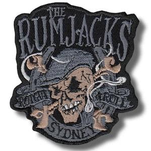May include: Embroidered patch with a skull in a pirate hat, crossed swords, and the words "THE RUMJACKS" and "SYDNEY". The patch is mainly black, with grey, tan, and white details. The design has a distressed, vintage appearance.