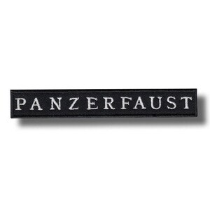 May include: A black rectangular patch with the word "PANZERFAUST" embroidered in white. The patch is a simple, rectangular shape, with the text centered horizontally.