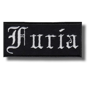 Op de afbeelding: Een zwart rechthoekig embleem met het woord "Furia" geborduurd in witte gotische letters. De patch heeft een lichte schaduw, wat suggereert dat deze verhoogd is.