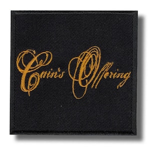 Peut inclure: Écusson carré noir avec texte doré brodé « Cain's Offering » en écriture cursive. L'écusson a un aspect texturé et une ombre subtile.