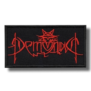 Può includere: Toppa rettangolare nera con testo ricamato rosso e simbolo simile a un pentagramma. Il testo "DEMONIXC" è scritto in un carattere gotico. Ideale per abbigliamento o accessori.