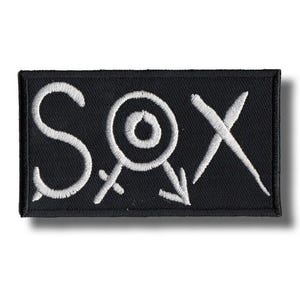 Op de afbeelding: Zwart rechthoekig embleem met wit geborduurde tekst "SOX". De "O" is een cirkel met een kleinere cirkel erin, en de "X" is een gestileerd kruis. De patch is waarschijnlijk voor kleding of accessoires.