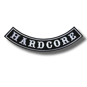 Puede incluir: Un parche negro curvado con la palabra "HARDCORE" bordada en blanco, contorneada en blanco. El parche tiene un borde negro y probablemente está diseñado para ser cosido en ropa o accesorios.