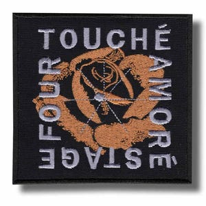 Könnte beinhalten: Quadratischer schwarzer Aufnäher mit gesticktem Text und Rosendesign. Der Text lautet "TOUCHÉ AMORE" und "FOUR STAGE" in silbernem Faden. Die Rose ist in Braun- und Goldtönen gehalten.