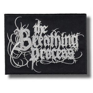 Puede incluir: Parche rectangular negro con el texto "The Breathing Process" en plata, con letras de estilo gótico. El texto está rodeado de remolinos decorativos. Ideal para chaquetas o bolsos.