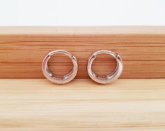 May include: A pair of silver hoop earrings. The earrings are small and have a simple design.