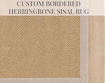 Puede incluir: Una alfombra de sisal color canela con un patrón de espiga tejido y un borde ancho de tela gris claro sólido. El texto CUSTOM BORDERED HERRINGBONE SISAL RUG está impreso en negro en el centro de la superficie de la alfombra con una fuente serif.