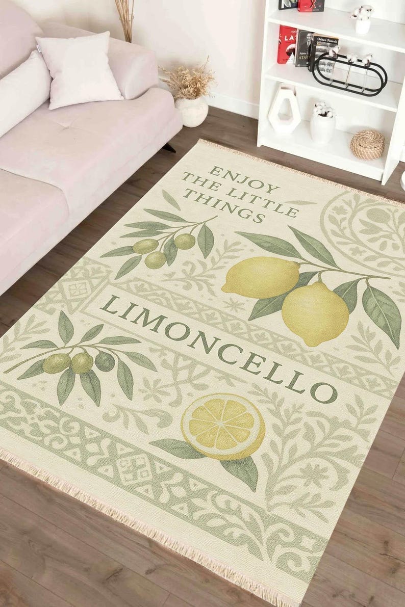 Pode incluir: Tapete retangular creme com um design de lim&atilde;o e ramos de oliveira. O tapete apresenta as palavras "Enjoy the little things" e "Limoncello". O tapete tem detalhes em verde e amarelo.