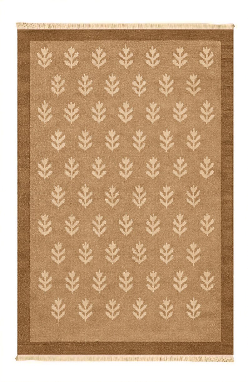 a rug with a repeating pattern of white leaf-like designs on a beige background.
