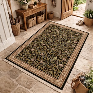 a large rug with a green and black floral design, placed on a stone floor in a room with a wooden table and a basket.