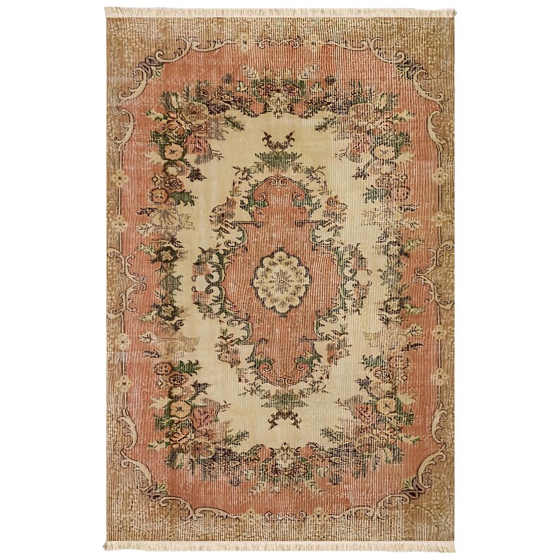 May include: A rectangular, vintage-style rug with a central cream-colored field and a surrounding border in a muted coral hue. The rug features a floral pattern with accents of green and brown, and a fringed edge.