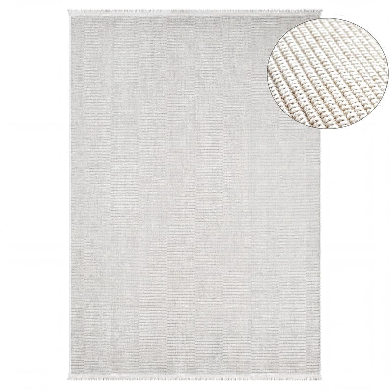 a large, plain grey rug with a fringed edge.