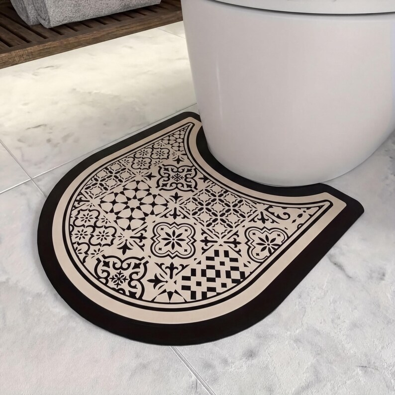A decorative black and white patterned mat is placed on a white tiled floor next to a white toilet.
