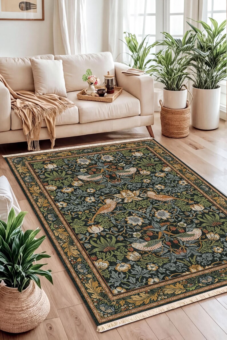 a cozy living room with a large, ornate rug featuring a floral design in shades of green and gold. The room is furnished with a white sofa, a wooden coffee table, and several potted plants. The arrangement of the furniture and the rug creates a harmonious and inviting atmosphere.