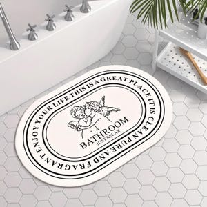 a bathroom with a white oval-shaped bath mat with a decorative design and text on it.