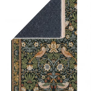 a detailed tapestry with a floral and bird motif, including various shades of green, orange, and white. The tapestry is folded in half, revealing a dark blue background.