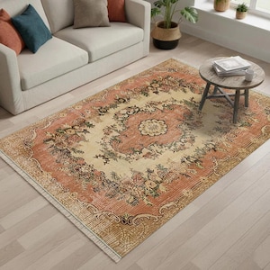May include: A rectangular area rug with a floral pattern in shades of peach, cream, and green. The rug features a central medallion design surrounded by a border of stylized flowers and leaves. The rug has a distressed, vintage look.