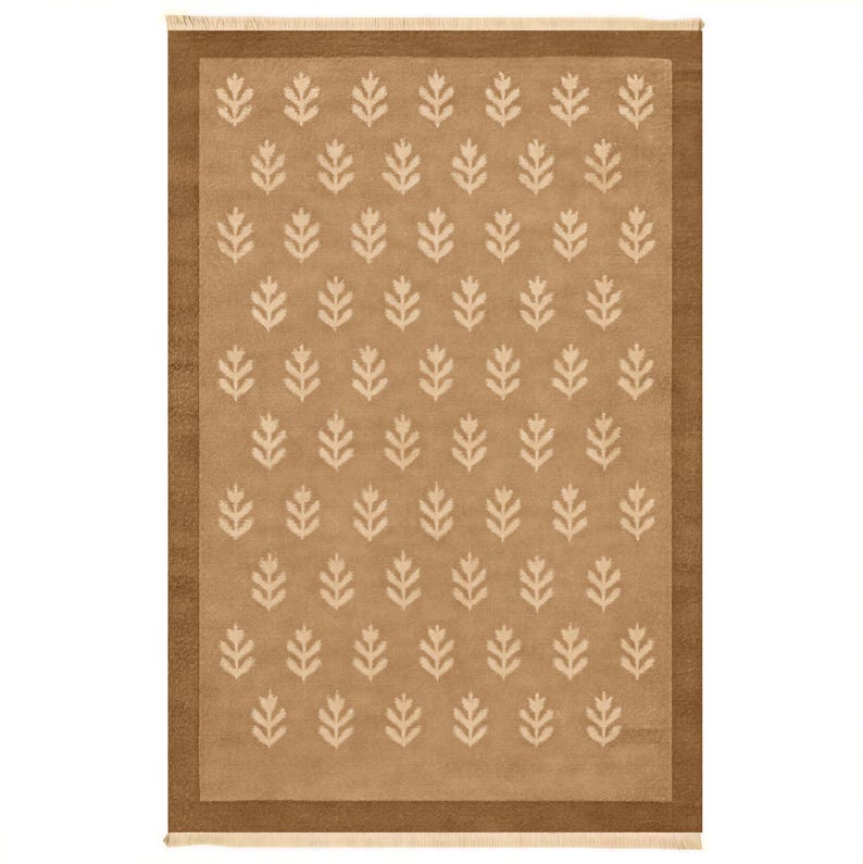a rectangular rug with a repeating pattern of white leaf-like designs on a beige background.