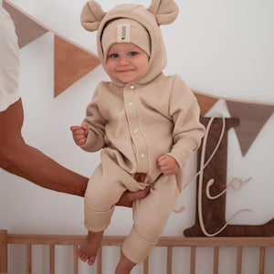 May include: A white ceramic mug with a black handle and the text "But First, Coffee" in a black, handwritten-style font. The mug is on a white surface.