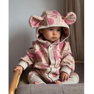 May include: A pink and cream baby onesie with a lemon print and bear ears on the hood. The onesie has a zip fastening and is made of soft, comfortable fabric.