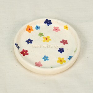 May include: A small, off-white ceramic dish decorated with colorful flowers in shades of orange, blue, pink, yellow, and green. The words "Best Wife Ever" are inscribed in the center of the dish.