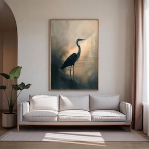 Könnte beinhalten: Gerahmter Kunstdruck mit einer Silhouette eines Reihers im Wasser. Das Kunstwerk verwendet eine gedämpfte Farbpalette mit Blau-, Grau- und Goldtönen. Der Reiher ist der Mittelpunkt, vor einem weichen, verschwommenen Hintergrund.