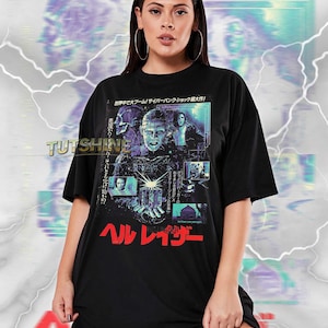 May include: Black unisex t-shirt featuring a graphic from the movie Hellraiser. The design includes images of characters and Japanese text. The shirt has the text "TUTSHINE" printed on the front.