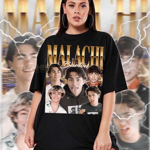 May include: Black t-shirt with a gold-coloured "MALACHI Barton" design and images. The shirt is worn by a person. The shirt is a unisex style. The text at the bottom of the image provides sizing information.