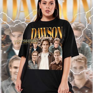 May include: Black unisex t-shirt featuring a graphic of the TV show "Dawson's Creek" cast. The shirt has the show's title in gold lettering. The model is wearing a 2XL shirt. The text "TUTSHINE" is also visible.