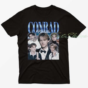 Könnte beinhalten: Schwarzes T-Shirt mit einer Collage von Bildern und dem Text "CONRAD Fisher" in einem blauen Farbverlauf. Die Collage enthält mehrere Bilder eines jungen Mannes in verschiedenen Posen, was eine Vintage-Ästhetik erzeugt.