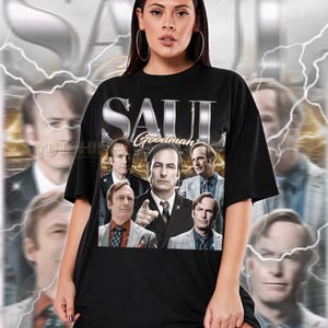 Peut inclure: T-shirt noir unisexe avec l'inscription argentée "SAUL GOODMAN" et un collage d'images d'un homme en costume. Le t-shirt est de taille standard. Le modèle porte une taille 2XL. Voir le tableau des tailles.
