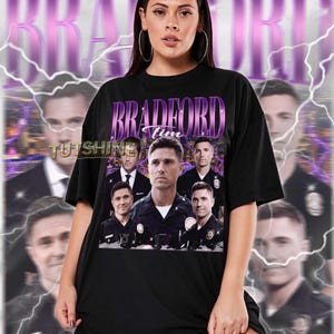 May include: Black unisex t-shirt featuring a graphic of a man with the text "BRADFORD Tim" in purple. The design includes multiple images of the same man in various poses. The shirt has a crew neck and short sleeves. The text "TUTSHINE" is also visible.