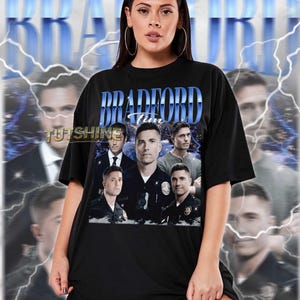 May include: Black unisex t-shirt featuring a graphic design with the text "BRADFORD Tim" in blue, along with images of several men. The shirt includes the text "TUTSHINE" and is a true-to-size fit.