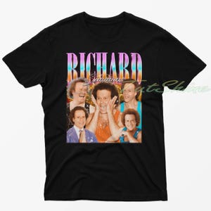 May include: Black t-shirt featuring a vintage-style graphic of Richard Simmons. The graphic is a collage of images of Richard Simmons in various poses, with the text "Richard Simmons" in a colourful, retro font.