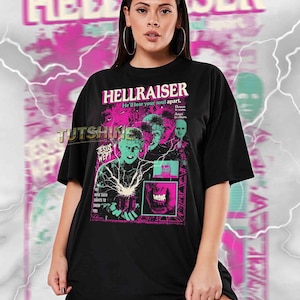 May include: Black t-shirt featuring the movie title "HELLRAISER" in pink and white, with a graphic of characters from the film. The shirt also includes the text "JESUS WEPT" and "HAVE SUCH SIGHTS TO SHOW YOU."