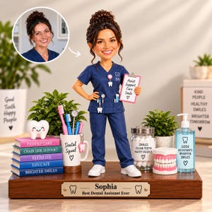 Op de afbeelding: Een gepersonaliseerd bobblehead-figuurtje van een tandartsassistent in marineblauwe scrubs, met een klembord waarop staat Assist Support Care Smile. Het figuurtje staat op een houten voet met een plaatje met de tekst Sophia Best Dental Assistant Ever.