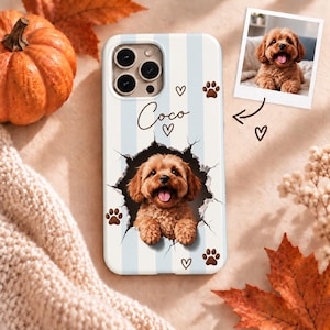 May include: A phone case with light blue and white vertical stripes, featuring a custom graphic of a brown dog peeking through a cracked hole. The name Coco is printed in script above the dog, surrounded by small brown hearts and paw prints.