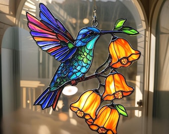 May include: A stained glass hummingbird with vibrant blue, green, and rainbow-coloured wings perches on a branch with orange bell-shaped flowers. The decorative piece hangs from a chain, suitable for window or wall decor.