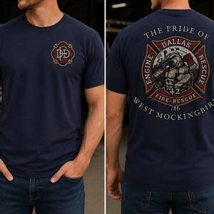 May include: A navy blue short-sleeve t-shirt featuring a small red and gold fire department logo on the front chest and a large graphic on the back. The back design displays an eagle, an axe, and the text The Pride of Dallas Engine Rescue 42 Fire-Rescue 786 West Mockingbird.
