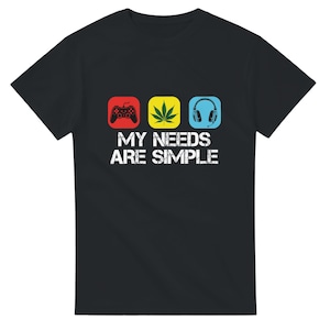 Könnte beinhalten: Schwarzes T-Shirt mit dem weißen Text "MY NEEDS ARE SIMPLE". Das Design umfasst ein rotes Quadrat mit einem Gamecontroller, ein gelbes Quadrat mit einem Cannabisblatt und ein blaues Quadrat mit Kopfhörern.