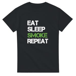 Könnte beinhalten: Schwarzes T-Shirt mit dem Text "EAT SLEEP SMOKE REPEAT" in verblichener weißer Schrift, wobei das Wort "SMOKE" grün ist. Das T-Shirt hat einen Rundhalsausschnitt.