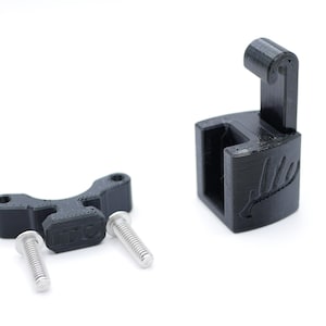 May include: A black 3D-printed bracket and mounting hardware set. The set includes a bracket with two screw holes, two silver screws, and a larger, angled bracket with a curved top. The larger bracket has a leaf design.