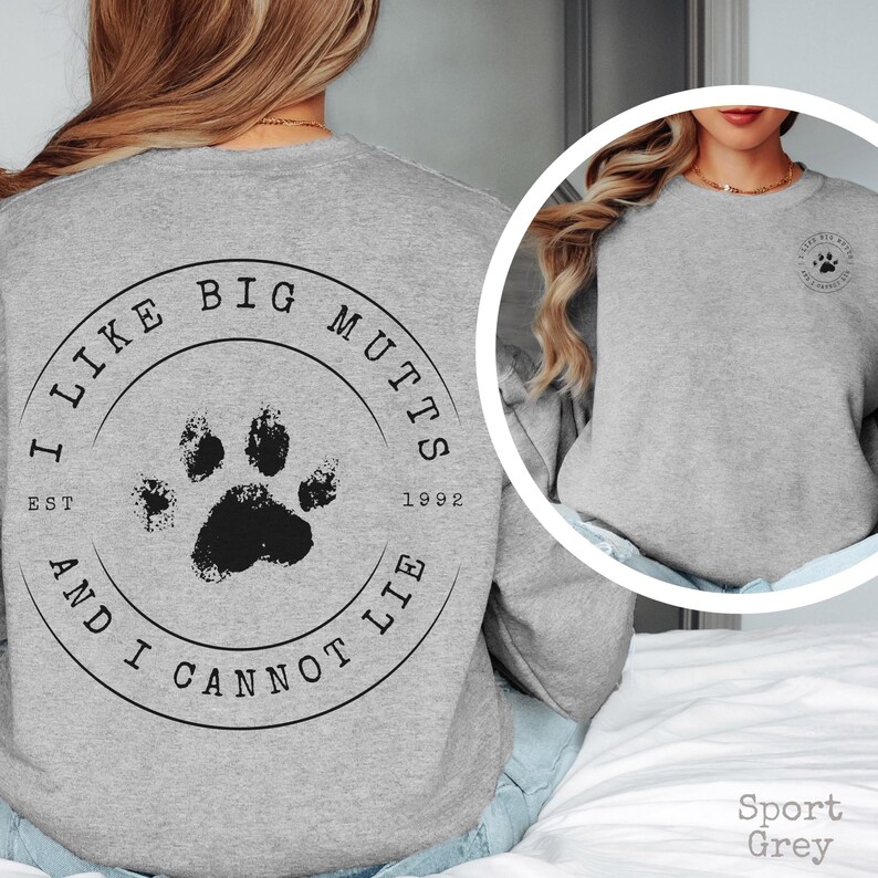 K&ouml;nnte beinhalten: Ein sportgrauer Rundhals-Pullover mit einer gro&szlig;en, kreisf&ouml;rmigen schwarzen Grafik auf der R&uuml;ckseite, die einen Pfotenabdruck in der Mitte und den Text I LIKE BIG MUTTS AND I CANNOT LIE EST 1992 zeigt. Eine kleinere Version ist auf der Brust.