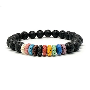 May include: A black lava stone bracelet with a mix of colorful, patterned beads. The bracelet features large, round, porous black beads interspersed with smaller, cylindrical beads in various colors, including white, pink, blue, brown, red, yellow, green, and purple.