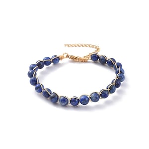 May include: A beaded bracelet featuring dark blue, round beads strung on gold-colored wire. The bracelet has a gold-colored chain for adjustable sizing. The beads are approximately 0.3 inches in diameter.
