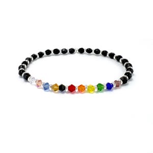 May include: A black beaded bracelet with a rainbow of colored crystal beads. The bracelet is made with small, round black beads and features a row of colorful crystal beads in the colors of the rainbow.